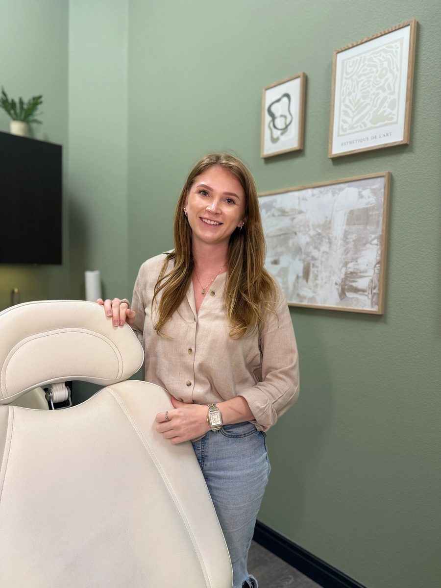 Lindsay standing behind the cream treatment chair in her sage-green studio suite