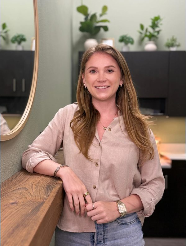 Lindsay smiling and leaning on the oak shelf in her Austin studio