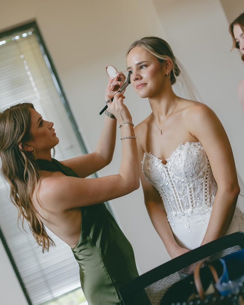 Lindsay finishing a bride's makeup with a powder brush on the wedding morning