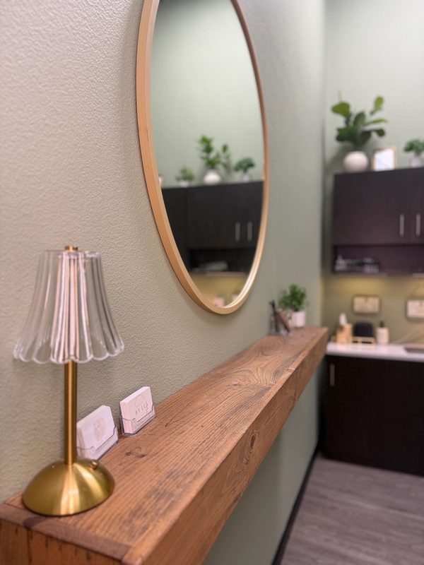 Brass fluted lamp on the oak shelf under a round mirror in the studio